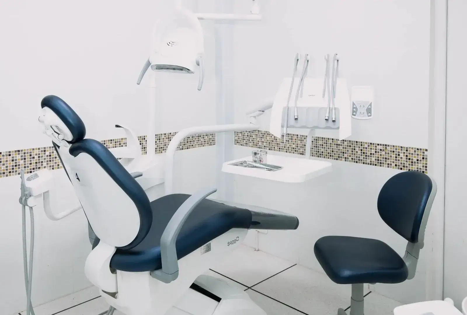 Cabinet dentaire moderne aux surfaces immaculées, fauteuil bleu marine et équipements parfaitement propres