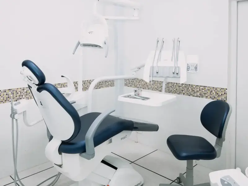 Cabinet dentaire moderne aux surfaces immaculées, fauteuil bleu marine et équipements parfaitement propres